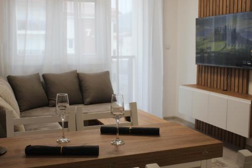 a living room with two wine glasses on a table at Apartmani Fontana Banja Koviljaca in Banja Koviljača