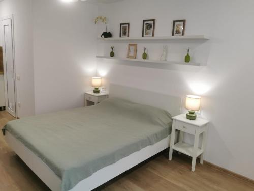 a white bedroom with two tables and two lamps at Happy Home1 in Cahul