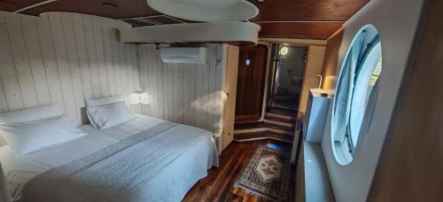 a bedroom with a bed in a room with a window at Péniche ALEGRIA in Poilhès