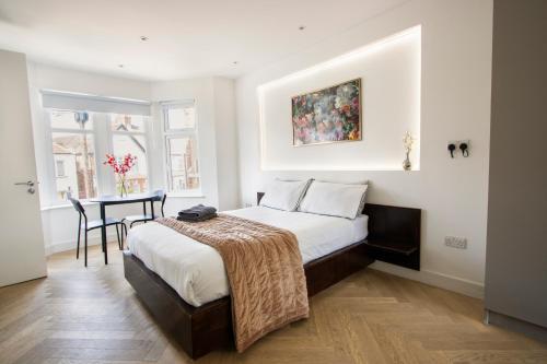 a bedroom with a bed and a table in it at Harrow Boutique Suites in Harrow