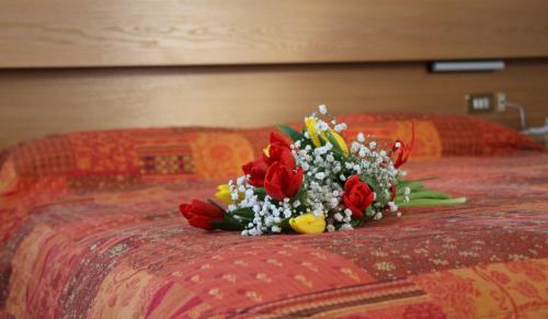 a bouquet of flowers sitting on a bed at Hotel Garni Ongaro in Selva di Cadore