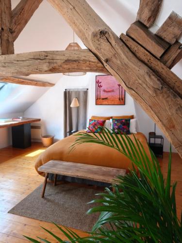 a bedroom with a large bed and a bench at La petite maison d'à côté in Noyers