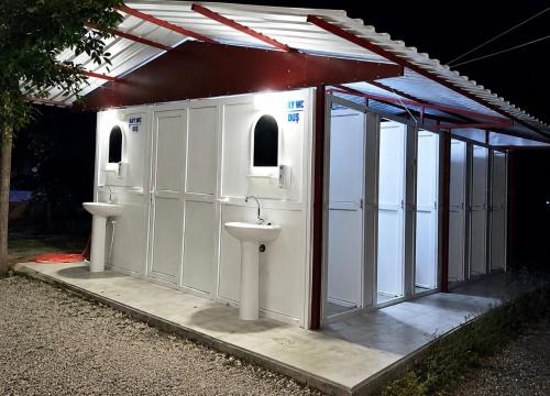 a white building with two toilets and a sink at Çıralı Camping in Cıralı