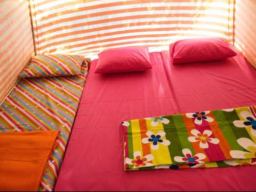 a bed with colorful sheets and pillows on it at Çıralı Camping in Cıralı
