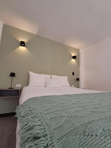 a white bedroom with a large bed with a green blanket at 7min del Parque Central-2min Rotonda Marimba, en la naturaleza Tipo LOFT5 in Quetzaltenango