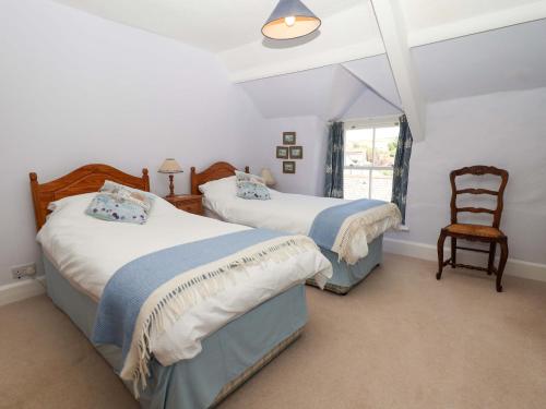 a bedroom with two beds and a chair at Agar Cottage in Port Isaac