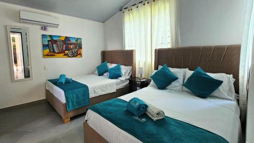 a hotel room with two beds with blue pillows at Cabaña Los Cristales Coveñas by Amauna in Coveñas