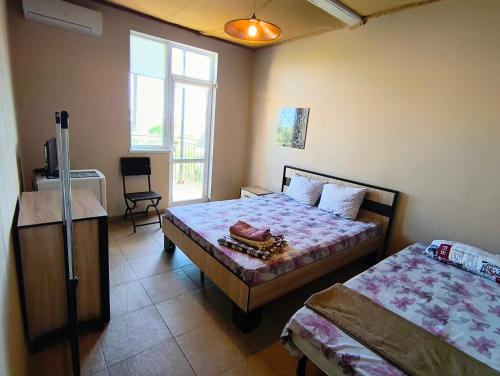 a bedroom with two beds and a chair and a window at Guest House Dacha in Karolino-Buhaz