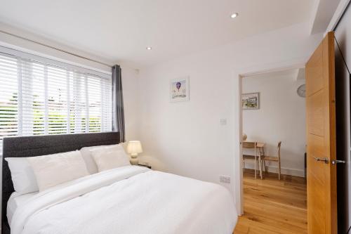 a white bedroom with a large bed and a window at Sunnymede Court in Billericay