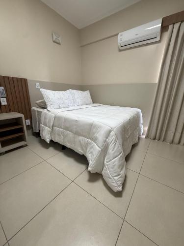 a bedroom with a bed with white sheets and a window at Spazzio diRoma Caldas Novas in Caldas Novas