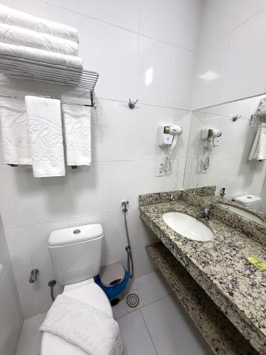 a bathroom with a toilet and a sink and towels at Spazzio diRoma Caldas Novas in Caldas Novas
