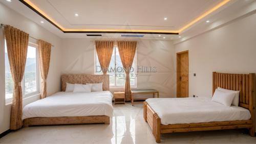two beds in a room with two windows at Diamond Hills Resort in Battakundi