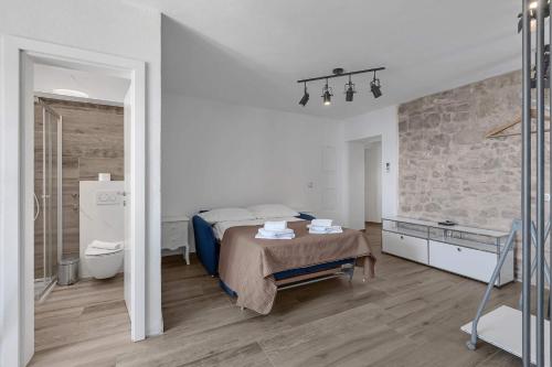 a white bedroom with a bed and a bathroom at Holiday Home Pelegrin in Brela