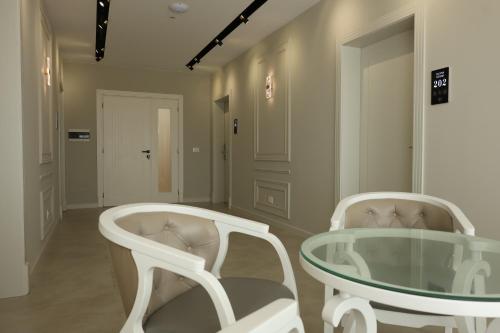 two white chairs and a glass table in a room at Olivia Hotel in Durrës