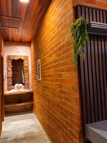 a brick wall in a hallway with a mirror at Vila do Sossego in São Bento do Sapucaí