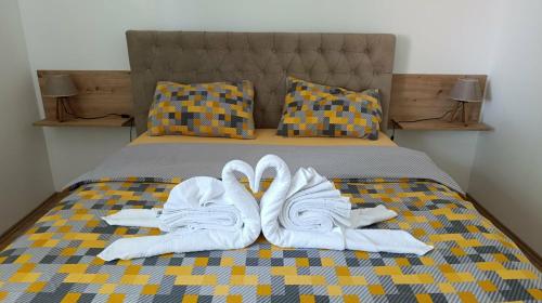 two pairs of white shoes and towels on a bed at Apartman Pavlov 023 in Zrenjanin