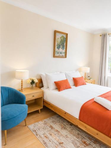 a bedroom with a bed and a blue chair at Ashwood Stays in Surbiton