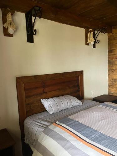 a bed with a wooden headboard in a bedroom at Hermosa cabaña de lujo MADERA in Tochimpa