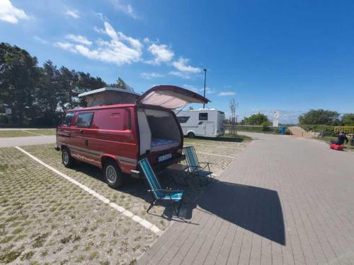 a red van parked in a parking lot with a camper at Retro Kamper Jastarnia in Jastarnia