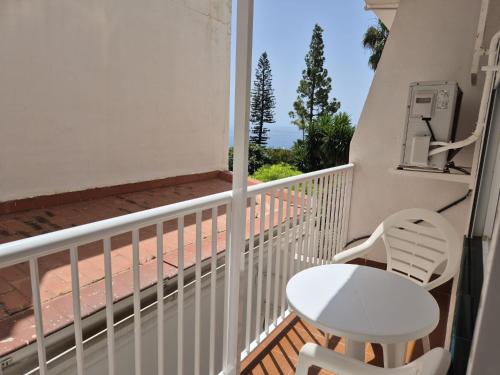 ein Balkon mit einem weißen Stuhl und einem Tisch in der Unterkunft 1ºB Escobar in Nerja