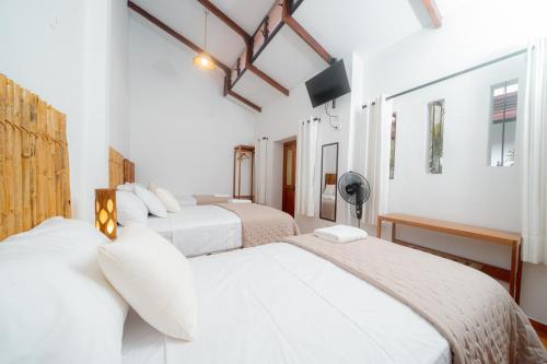 two beds in a room with white walls at Muyuterra in Moyobamba