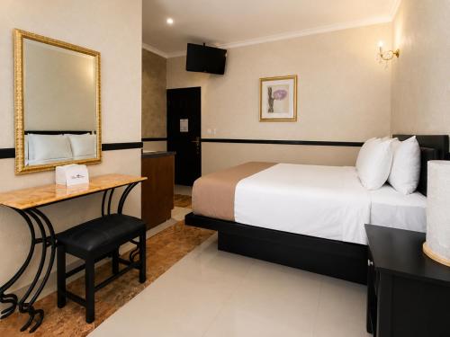 a hotel room with a bed and a desk and a mirror at Hotel Palacio Maya in Mérida