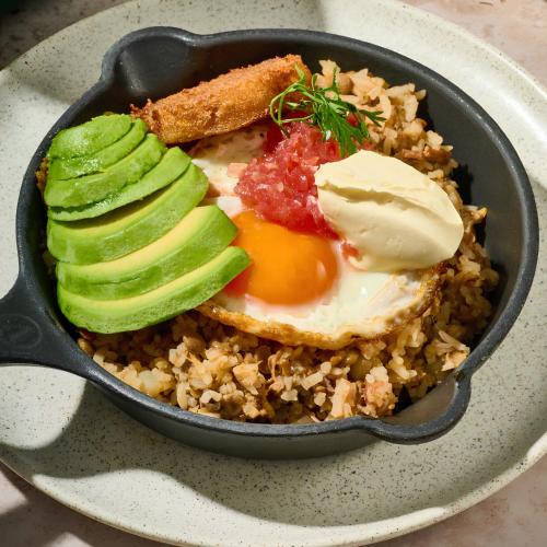 a pan of food with eggs and vegetables on rice at Urbit Garden Hotel in Medellín