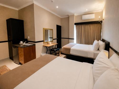a hotel room with two beds and a desk at Hotel Palacio Maya in Mérida