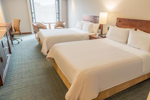 a hotel room with two beds and a television at GHL Hotel Capital in Bogotá