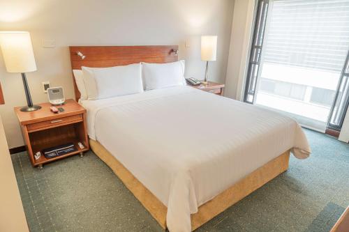 a bedroom with a large bed and a large window at GHL Hotel Capital in Bogotá
