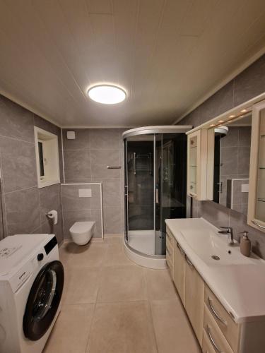 a bathroom with a shower and a washing machine at Unique Villa by a beautiful lake in Omberg