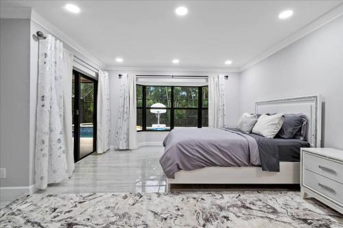 a white bedroom with a bed and a large window at Elegant, 4 BDR house with a pool and BBQ in Wellington