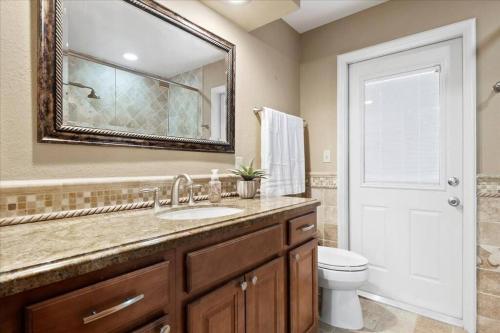 a bathroom with a sink and a toilet and a mirror at Elegant, 4 BDR house with a pool and BBQ in Wellington