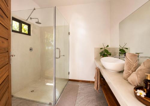 a bathroom with a glass shower and a sink at CosyBe Villas in Praia do Tofo