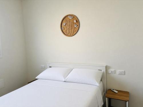 a bedroom with a white bed and a clock on the wall at La Curt by Ambroeus apartments in Inzago