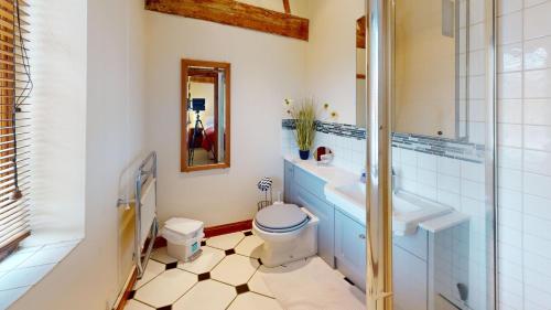a bathroom with a toilet and a sink and a mirror at The Byre in Banbury