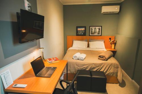 a bedroom with a bed and a desk with a laptop at Rio Branco 688 - Hospedagem Premium in Santa Maria