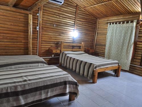 two beds in a room with wooden walls at Las Cabañas in Santo Tomé