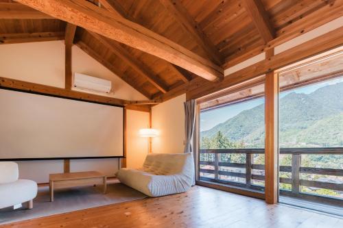 a living room with a chair and a large window at Nakasendo Shiki - Private Garden Villa in Nagiso