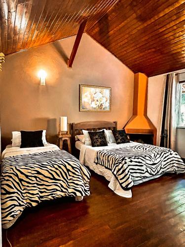 two beds in a room with zebra sheets at Pousada Alto do Vale in Nova Friburgo