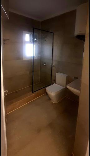 a bathroom with a toilet and a glass shower at Virginia beach village in El Alamein