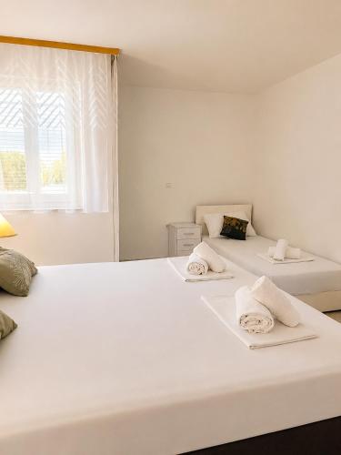 two white beds in a room with a window at Apartmani Morѐll 1 in Novalja
