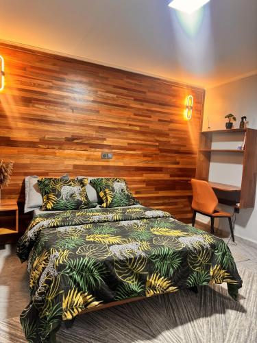 a bedroom with a large bed with a wooden wall at Le Cocon de Jade - Nylon Bastos in Yaoundé