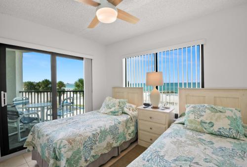 a bedroom with two beds and a balcony at Caprice Resort by Travel Resort Services in St. Pete Beach