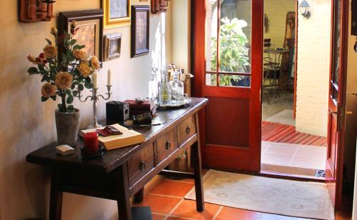 a room with a wooden table with a vase of flowers at Goblin's Mead in Edgemead
