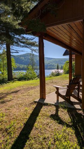 Eine Bank unter einer Veranda mit Blick auf einen See in der Unterkunft L'Ours Bleu in Lac-Saguay