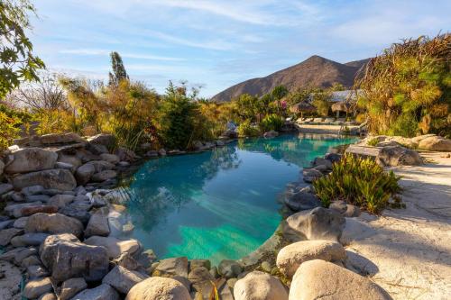 a pool of water with rocks and a mountain at Hotel Boutique Refugio El Molle in El Molle