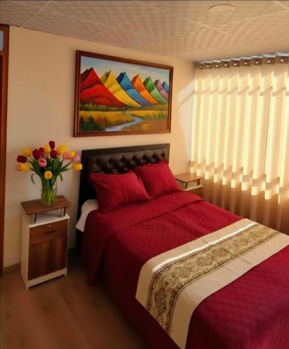a bedroom with a red bed with a vase of flowers at APART SExTA ESTACIÓN in Juliaca