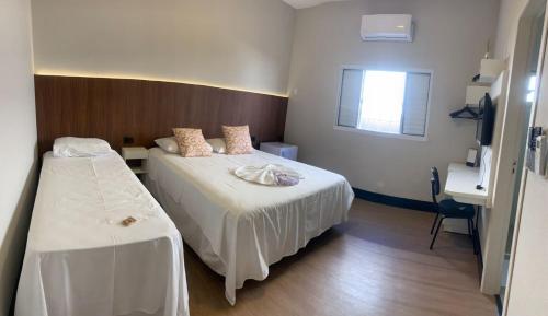 a hotel room with two beds and a desk at Hotel Iaguara in Coxim
