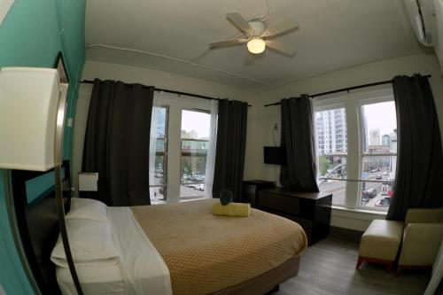 a bedroom with a bed with a ceiling fan and windows at California Dreams Hostel - Downtown in San Diego